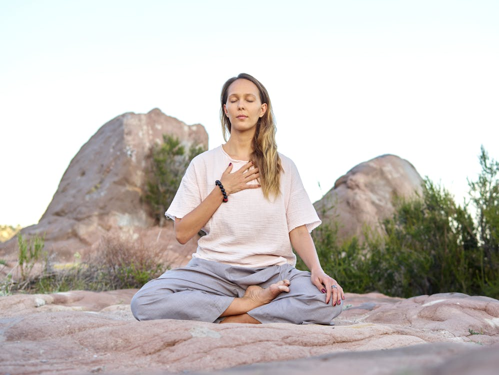 Finding Inner Calm Through Deep Meditation A woman sitting on a rock under the sky. Eyes closed and meditating
